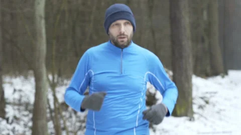Young man jogging in winter forest and checking time on phone Stock Footage 95139959