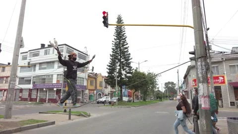 Young man juggling and doing tightrope begging on a traffic light in Bogotá Stock Footage 150904150