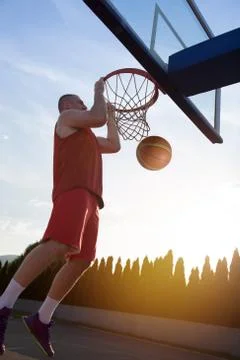 Young man jumping and making a fantastic slam dunk playing stree Фото