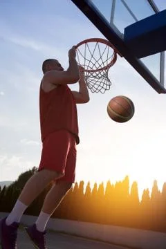 Young man jumping and making a fantastic slam dunk playing stree Foto stock
