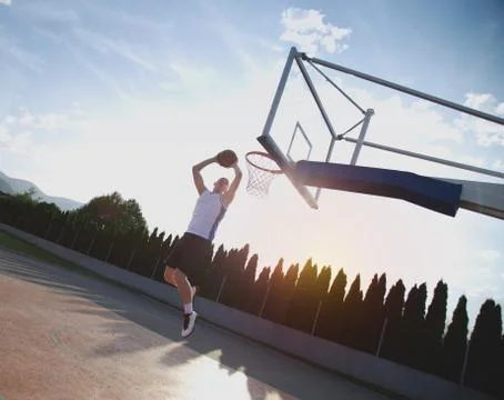 Young man jumping and making a fantastic slam dunk playing stree Stock Photos