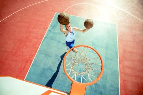 Young man jumping and making a fantastic slam dunk playing streetball Stock Photos