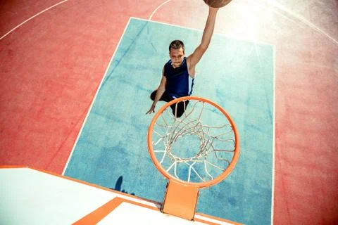 Young man jumping and making a fantastic slam dunk playing streetball Stock Photos