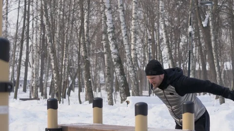 Young man jumping on bench in winter park during crossfit training outdoor Stock Footage 87966738