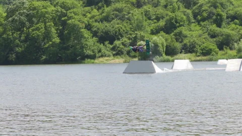 Young man jumping on the ramp with his wakeboard and doing front and backflips Stock Footage 157534882