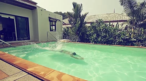 Young man is jumping to swimming pool in a villa Stock Footage 56866153