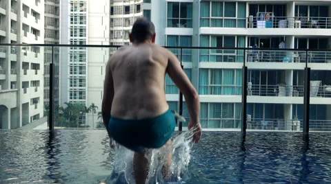 Young man jumping to swimming pool, super slow motion 240fps Stock Footage 63435424