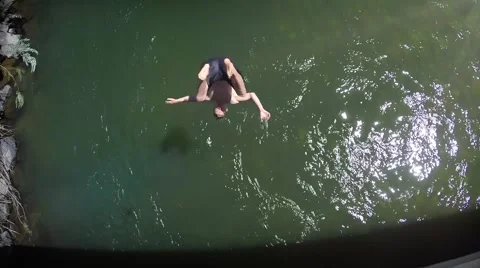 Young man jumps off a bridge, flips and crashes into the river in slow-mo Stock Footage 41774023