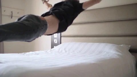 Young man jumps onto a large bed from a height slow motion shot Vídeos de archivo 115434559