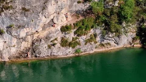 A young man jumps over rocks and dives into the waters of a beautiful valley Video stock 284987076