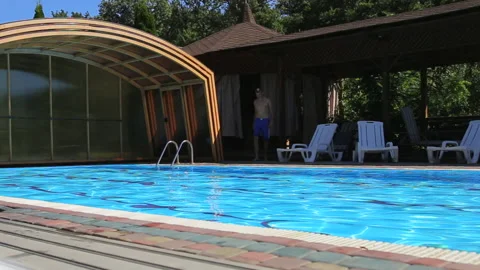 Young man jumps into the pool. Relax by the pool on a sunny summer day. Close up Stock Footage 147102017