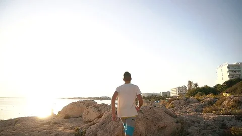 Young man jumps on rocks at the background of the sea in Cyprus Stock Footage 85202100