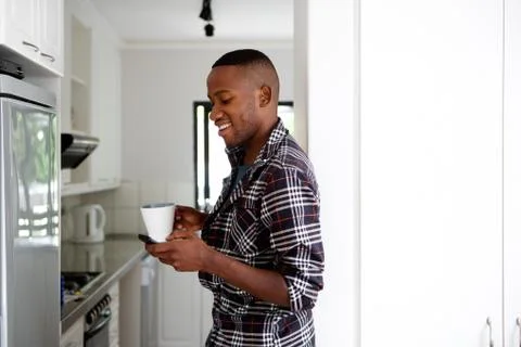 Young man in the kitchen with coffee using cell phone Stock Photos