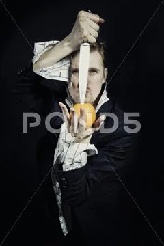 Young man with a knife and an orange Stock-Fotos