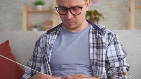 Young man with knitting needles in hand knits Stock Footage 107375567
