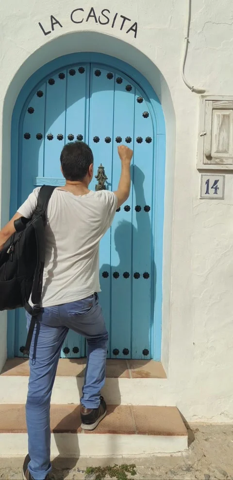 Young man knocking on a blue door Stock Footage 344692322