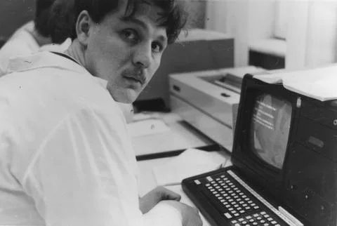Young man in lab coat working at vintage computer terminal 1980s 스톡 사진