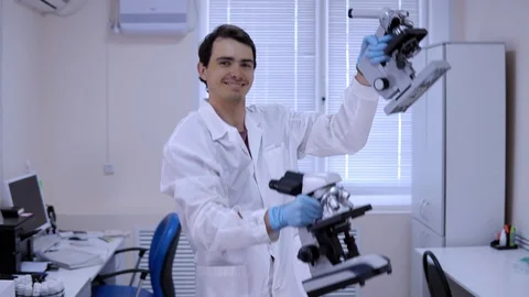 Young man laboratory technician is dancing in lab with microscopes in hands. Stock Footage 112620808