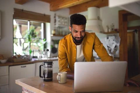 Young man with laptop and coffee working indoors, home office concept. Stock Photos