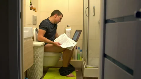 Young man with laptop and documents works on the toilet. 4K, slow motion Video stock 148394052
