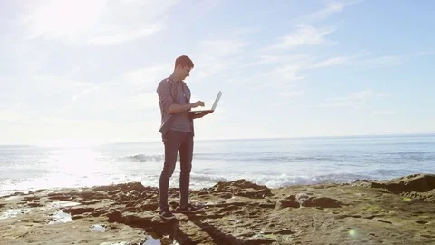 Young man with a laptop on a beach Stock Footage 75756926