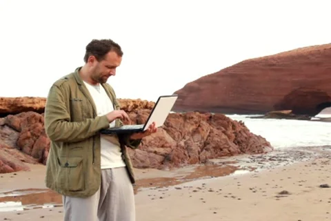 Young man with laptop computer on beautiful Legzira beach Stock Footage 10891764