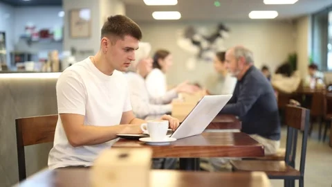 Young man with laptop drinking coffee Stock Footage 327135255