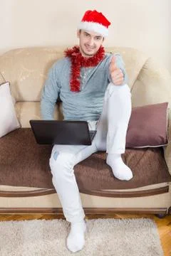Young man with laptop on a sofa. Businessman with Santa hat Stock Photos