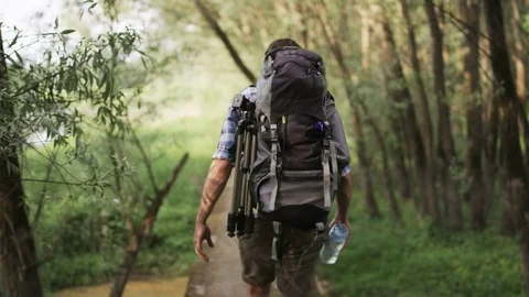 Young Man With a Large Rucksack Walking a Small Bridge Stock Footage 77676069