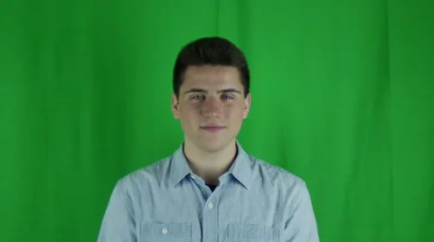 Young man laughing in a blue shirt in front of a greenscreen Vidéo 59089345