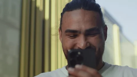 Young man laughing close up while reading on a smartphone a funny message from a Stock Footage 250626055