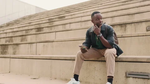 Young Man Laughing at Phone on Steps, head turning Stock Footage 318740475