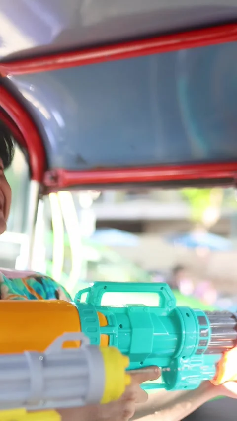 Young Man Laughing While Shooting Water Gun From Auto Rickshaw Stock Footage 335863725