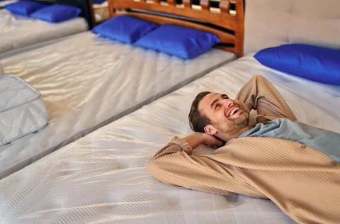 The young man lay down on the bed, trying the mattress for softness in the st Stock Photos