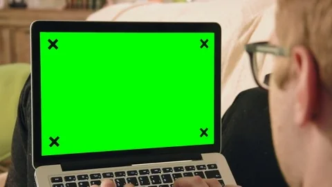 Young man laying on the sofa looking at laptop computer with green screen Stock Footage