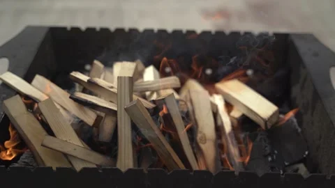 A young man lays chips on burning coals on a barbecue 4K Stock Footage 128800385