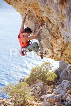 Young man lead climbing on overhanging cliff Stock Photos