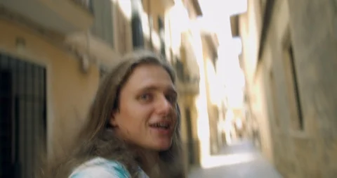 Young Man Leading with Hand in Spanish Old Town Street, Long Haired  Tourist  Stock Footage 94428512