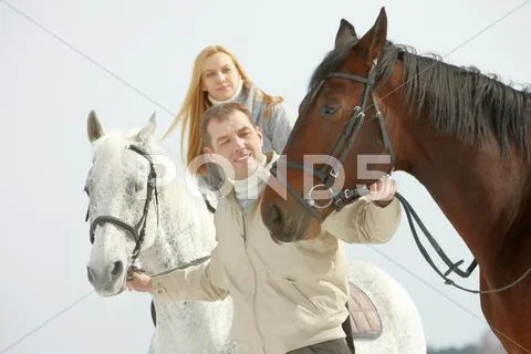 A young man leading two horses, one of them is ridden by a woman Stock Photos