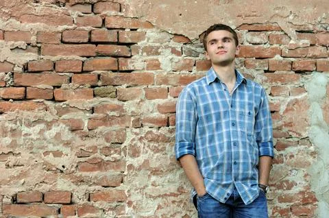 A young man leaned his back against an old brick wall, in thought. Stock Photos