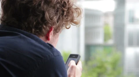 Young man leaning on windowsill, talking on the phone Stock Footage 41631216