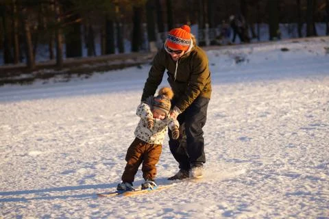 Young man learning his small child how to ski. Sunny photo on background of Stock Photos