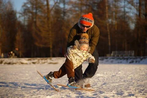 Young man learning his small child to ski. Smiling boy almast falling. Sunny Stock Photos