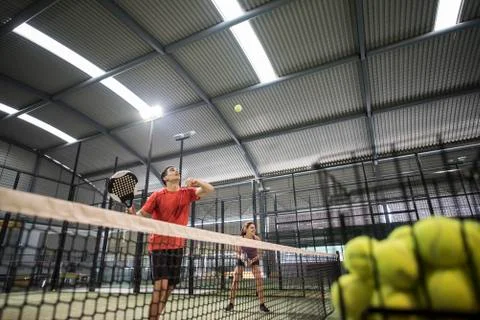 Young man learning how to play paddle tennis with his friend in the backgroun Stock Photos