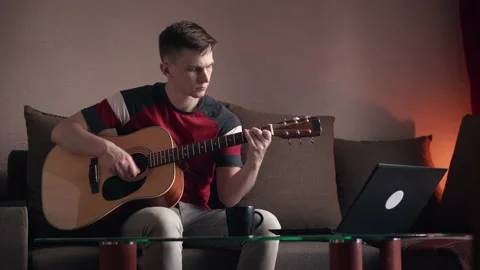 Young man is learn.ing to play the acoustic guitar. online learning. Stock Footage 207784282