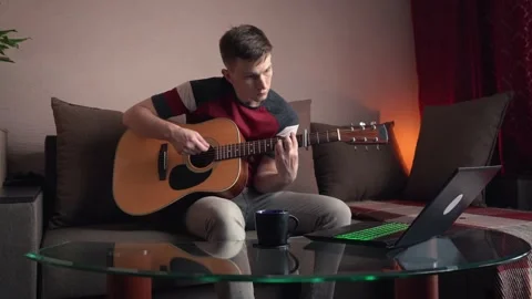 Young man is learn.ing to play the acoustic guitar. online learning. Vídeo Stock 207784474
