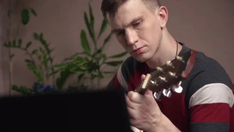 Young man is learn.ing to play the acoustic guitar. online learning. close-up Stock Footage 209308195