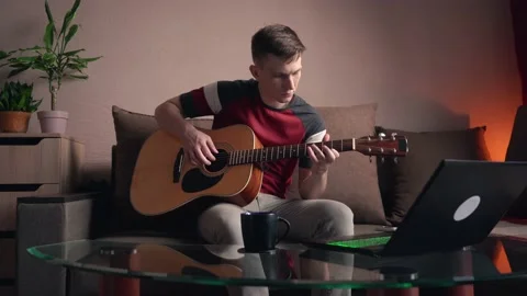 Young man is learn.ing to play the acoustic guitar. online learning. Stock Footage 210553996