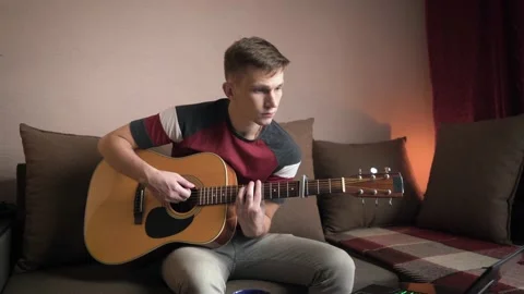 Young man is learn.ing to play the acoustic guitar. online learning. Stock Footage 210554083