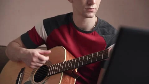 Young man is learn.ing to play the acoustic guitar. online learning. Stock Footage 211813149